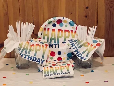 A table decorated with various Happy Birthday themed party supplies.